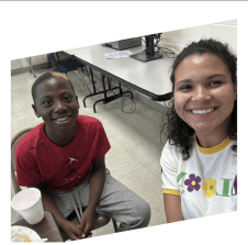 Mentor and child smiling together at a program table