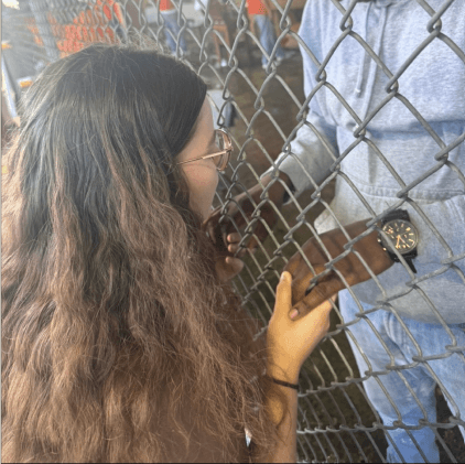 Hands clasped through a fence, symbolizing connection and second chances